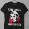 Das Bild zeigt ein schwarzes T-Shirt mit dem Anti Social Vampire Club Design. Das T-Shirt ist auf einem Kleiderhaken aufgehängt. Es wird verwendet, um einen Eindruck zu vermitteln, wie das reale Produkt letztendlich aussehen wird.