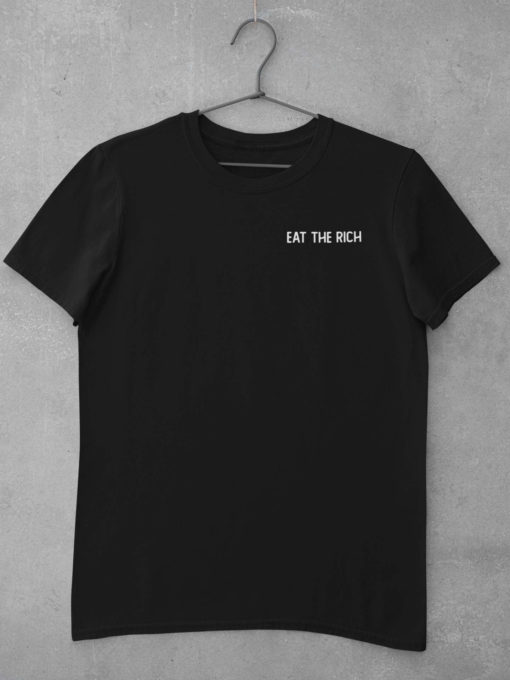 Das Bild zeigt ein schwarzes T-Shirt mit Eat The Rich Design (gestickt). Das T-Shirt ist auf einem Kleiderhaken aufgehängt. Es wird verwendet, um einen Eindruck zu vermitteln, wie das reale Produkt letztendlich aussehen wird.