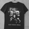 Das Bild zeigt ein schwarzes T-Shirt mit zwei lachenden, rauchenden Nonnen als Motiv. Das T-Shirt ist auf einem Kleiderhaken aufgehängt. Es wird verwendet, um einen Eindruck zu vermitteln, wie das reale Produkt letztendlich aussehen wird.
