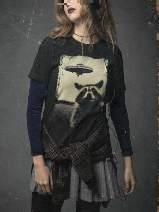 Das Bild zeigt eine Frau die das schwarze Weirdcore T-Shirt mit dem Waschbär trägt. Es wird verwendet, um einen Eindruck zu vermitteln, wie das Produkt an einem Menschen aussieht.