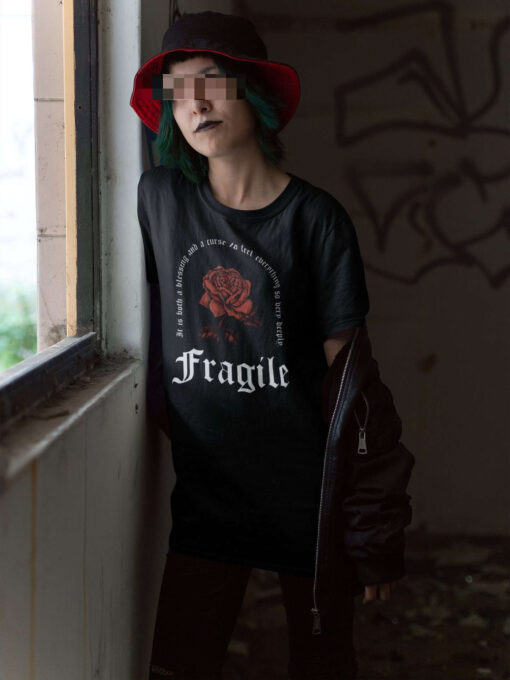 Emo E-Girl trägt schwarzes Unisex Relaxed Fit T-Shirt mit Fragile Gothic Rose Design.