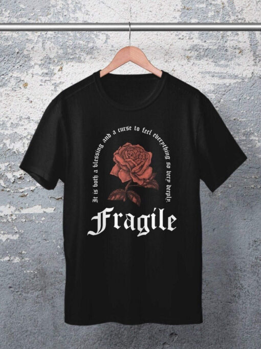 Unisex Relaxed Fit T-Shirt in schwarz mit Fragile Gothic Rose Design auf Kleiderbügel aufgehängt.